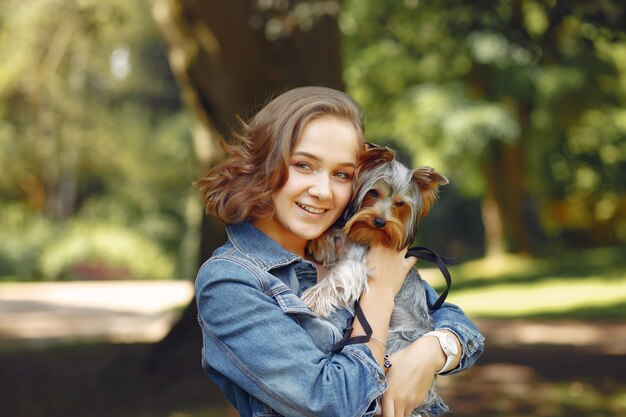 Nettes Mädchen in der blauen Jacke, die mit kleinem Hund spielt