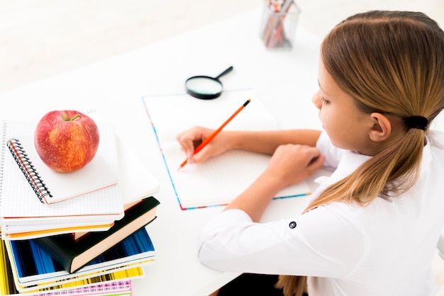 Nettes mädchen in der uniform studierend am schreibtisch