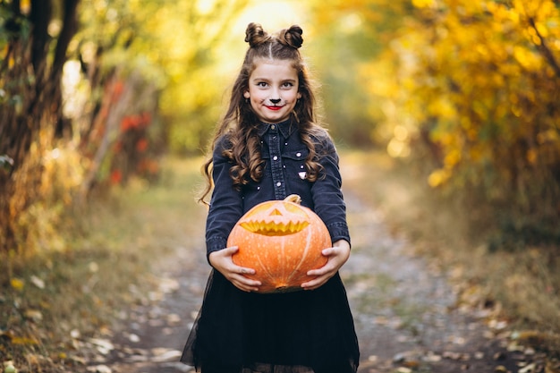 Nettes Mädchen kleidete im Halloween-Kostüm draußen mit Kürbisen an
