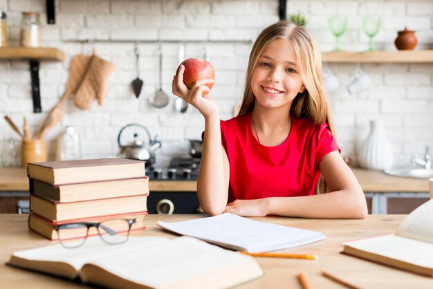 Nettes Mädchen mit Apfel zu Hause studierend