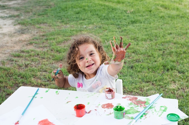 Nettes Mädchen mit den Händen gemalt in den bunten Farben