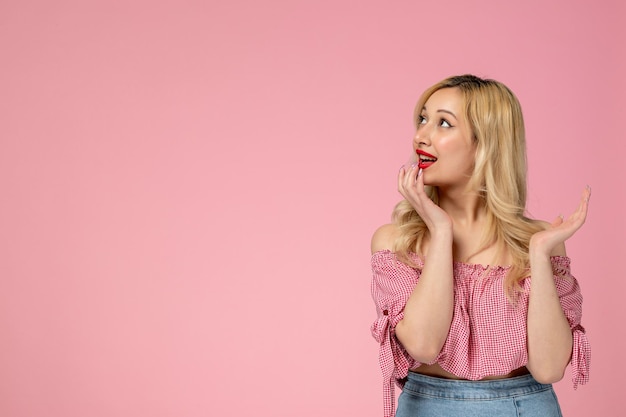 Nettes Mädchen, schöne junge Dame mit rotem Lippenstift in rosafarbener Bluse, die aufschaut und träumt