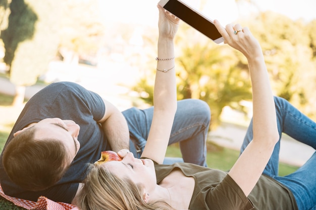 Nettes Paar, das Tablette auf Picknick verwendet