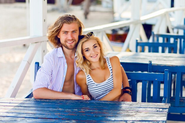 Nettes Paar in der Liebe umarmt und lächelt, sitzt am Tisch im gemütlichen Café am Strand