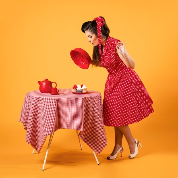 Nettes Pinup-Mädchen, das neben einigen Cupcakes steht