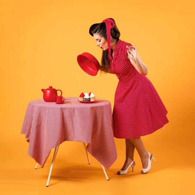 Nettes Pinup-Mädchen, das neben einigen Cupcakes steht