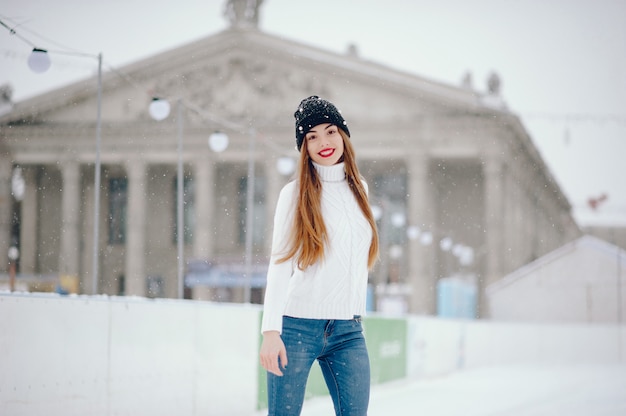 Nettes und schönes Mädchen in einer weißen Strickjacke in einer Winterstadt