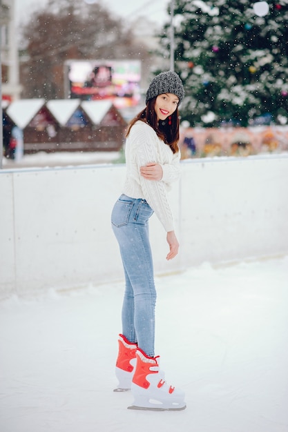 Nettes und schönes Mädchen in einer weißen Strickjacke in einer Winterstadt