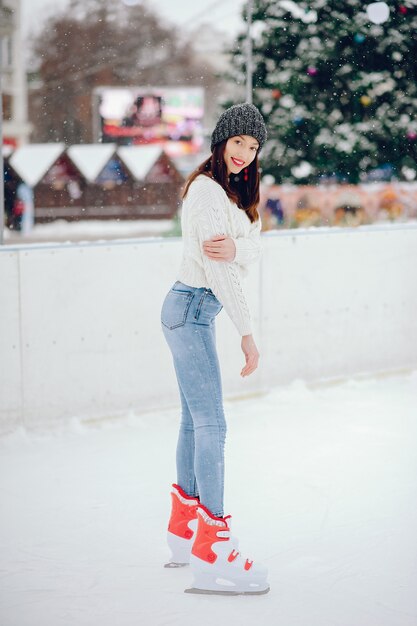 Nettes und schönes Mädchen in einer weißen Strickjacke in einer Winterstadt