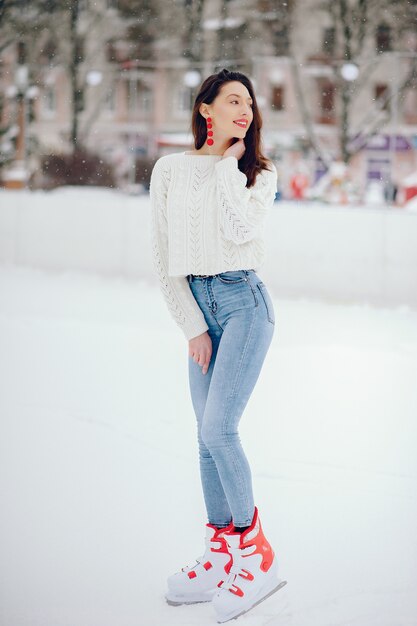 Nettes und schönes Mädchen in einer weißen Strickjacke in einer Winterstadt