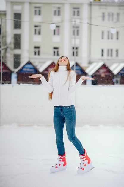 Nettes und schönes Mädchen in einer weißen Strickjacke in einer Winterstadt
