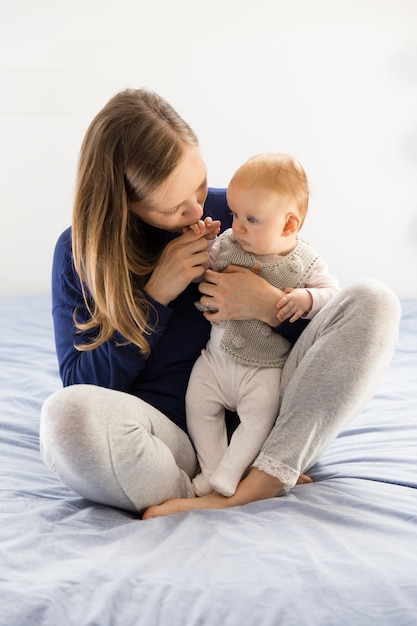 Neue Mutter, die entzückendes Baby kuschelt und küsst