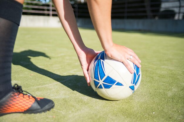 Neuer Fußballball auf Sportplatz. Blauer und weißer Fußball auf Sportplatz. Womans Hände, die es auf Gras setzen. Konzept für Fußball, Sport, Freizeitaktivitäten