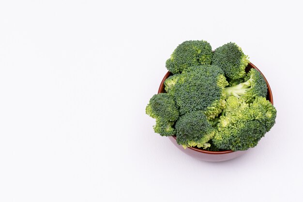 Neues Brokkolibündel grüner Brokkoli in der braunen keramischen Schüssel lokalisiert auf weißer Oberfläche