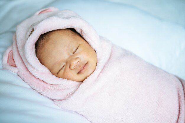 Neugeborenes Baby, das auf einer weichen rosa Decke schläft