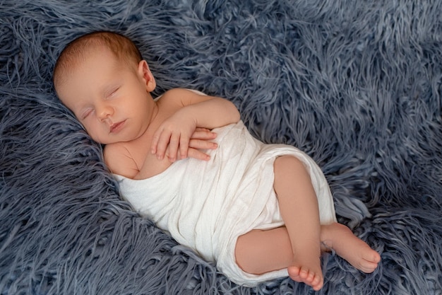 Neugeborenes Baby im Bett. Neugeborenes Kind schläft unter einer weißen Strickdecke. Kinder schlafen. Bettwäsche für Kinder. Säugling schläft im Bett. Gesundes kleines Kind kurz nach der Geburt. Textil mit Zopfmuster.