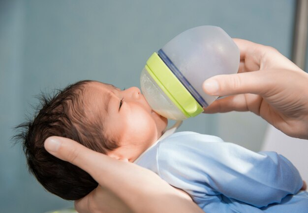 Neugeborenes Baby wird von der kleinen Flasche am Krankenhaus eingezogen