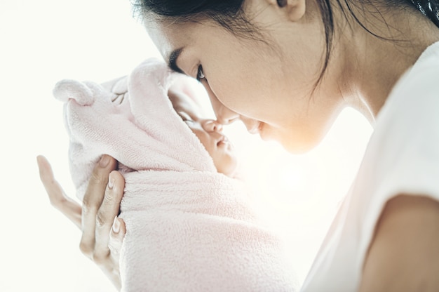 Neugeborenes, das in den Händen der Mutter und der Nase schläft, kollidierte