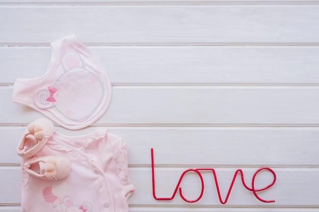 Neugeborenes Konzept mit Babykleidung und Liebesbriefen