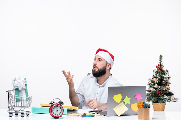 Neugieriger junger geschäftsmann im büro, der allein das neue jahr oder weihnachten feiert