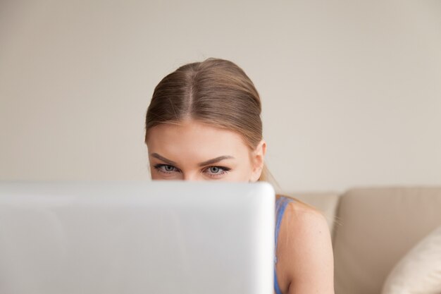 Neugieriges jugendlich unter Verwendung des Computers, junges lustiges Mädchen, das über Laptop späht