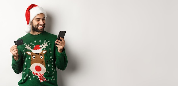 Kostenloses Foto neujahr online-shopping und weihnachtskonzept glücklicher bärtiger mann, der im internet mit kreditkarte kauft