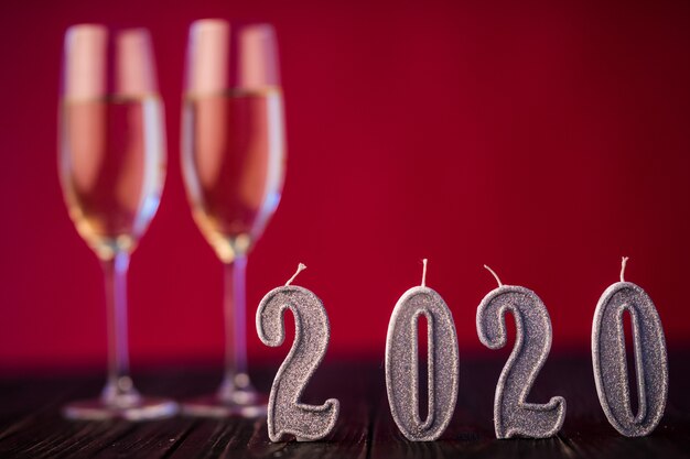 Neujahrsdekoration. Zwei Gobelts mit Champagner mit Weihnachts- oder Neujahrsdekoration 2020 auf Rotlichthintergrund
