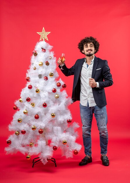 Neujahrsfeier mit bärtigem glücklichem jungem Mann, der ein Glas Wein hält und steht