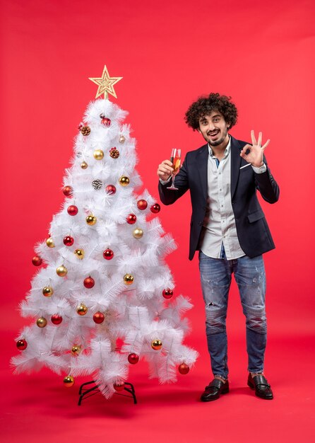 Neujahrsfeier mit bärtigem jungen Mann, der ein Glas Wein hält, das Brillengeste macht