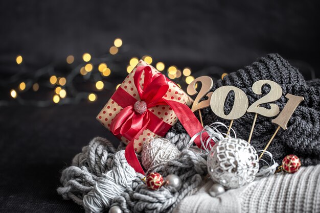 Neujahrskomposition mit hölzerner Neujahrszahl und Weihnachtsdekorationen auf einem dunklen Hintergrund.