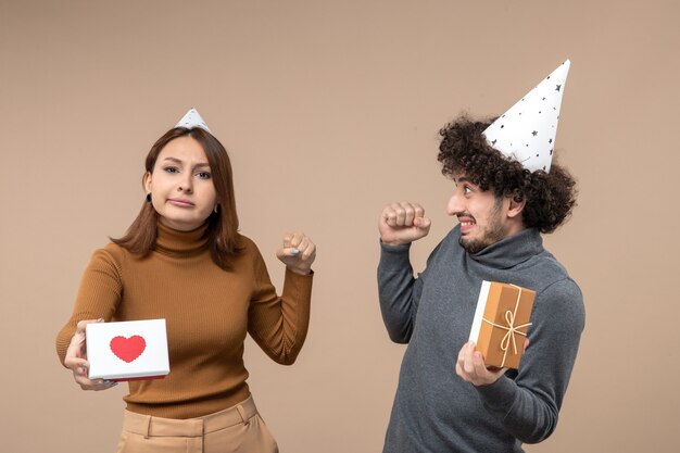 Neujahrsschießen mit emotionalem verrücktem schockiertem jungem Paar tragen Neujahrshutmädchen mit Herz