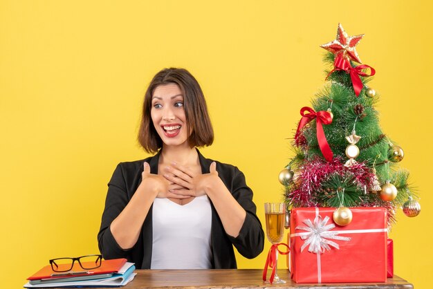 Neujahrsstimmung mit der schönen glücklichen Geschäftsdame, die sich überraschend zeigt und an einem Tisch im Büro sitzt