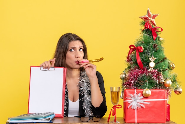 Neujahrsstimmung mit nachdenklich charmanter Dame im Anzug, der Dokument im Büro auf gelbem lokalisiert hält