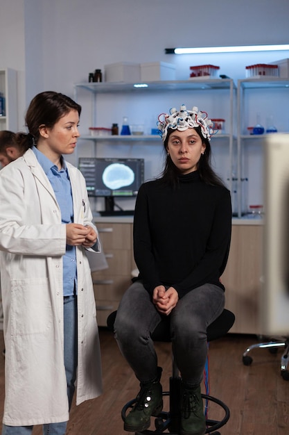Neurologe-Arzt, der einer Patientin mit einem EEG-Scanner während eines neurologischen Experiments im Labor Tomographie-Expertise zeigt, Facharzt, der die Gehirnentwicklung analysiert und die Aktivität des Nervensystems überwacht