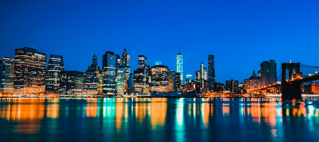 New york city manhattan midtown in der abenddämmerung mit wolkenkratzern beleuchtet über east river