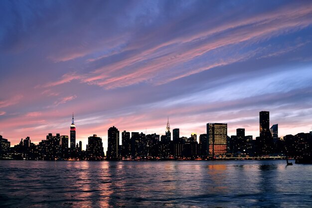 New York City Manhattan Midtown Silhouette Panorama bei Sonnenuntergang mit Wolkenkratzern und buntem Himmel über dem East River