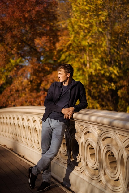 New York Manhattan Central Park im Herbst, Brücke über den See. Ein junger Mann geht in einem Herbstpark in New York spazieren.