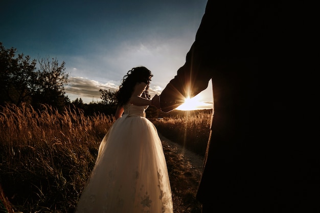 Newlyweds auf dem Gebiet bei Sonnenuntergang