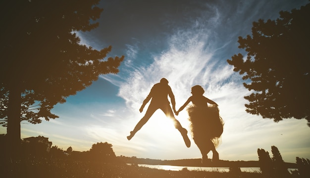 Newlyweds Springen in den Sonnenuntergang