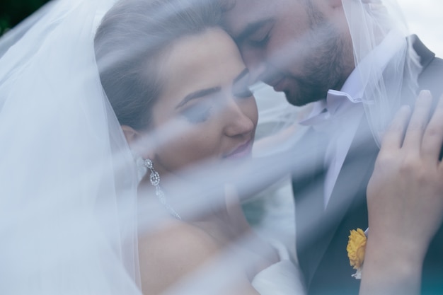 Newlyweds unter dem weißen Schleier