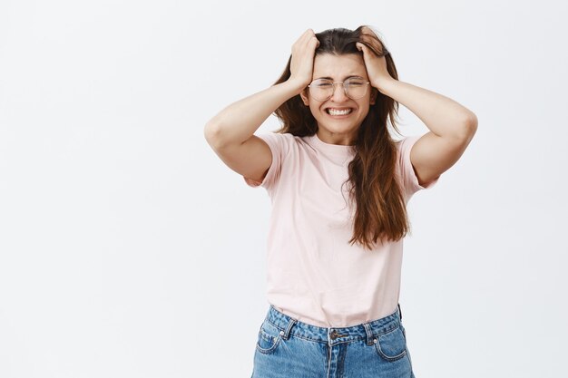 Ängstliche und panische junge Brünette mit Brille posiert