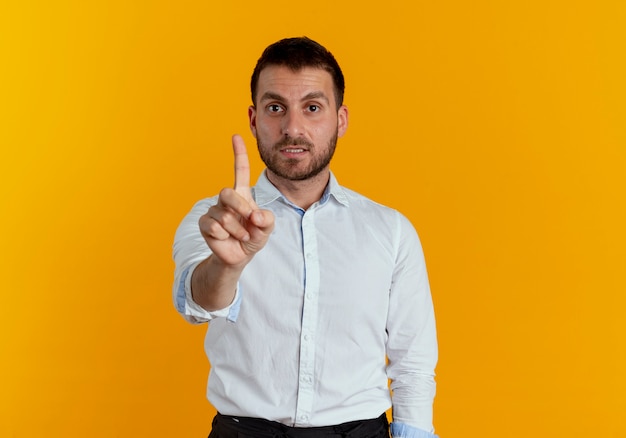 Ängstlicher gutaussehender Mann zeigt Zeigefinger isoliert auf orange Wand