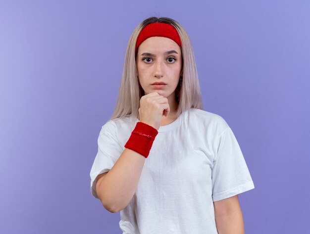 Ängstliches junges kaukasisches sportliches Mädchen mit Zahnspangen, die Stirnband tragen