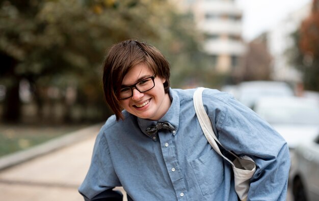 Nicht binäre Person mit Brille lächelnd