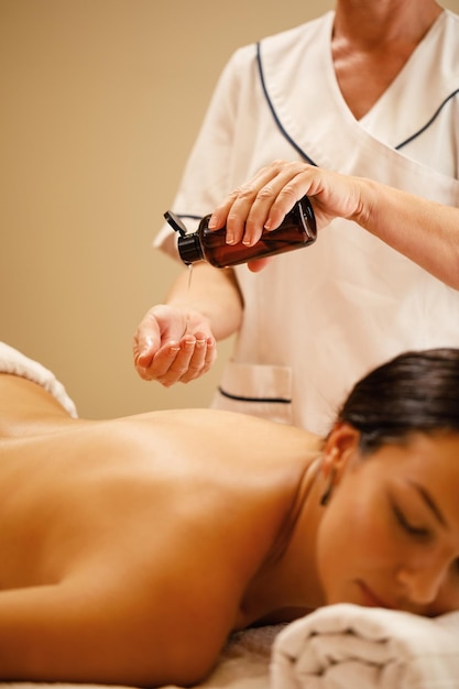 Nicht erkennbare Therapeutin, die vor der Massagebehandlung im Wellnesscenter Öl in ihre Hände gießt