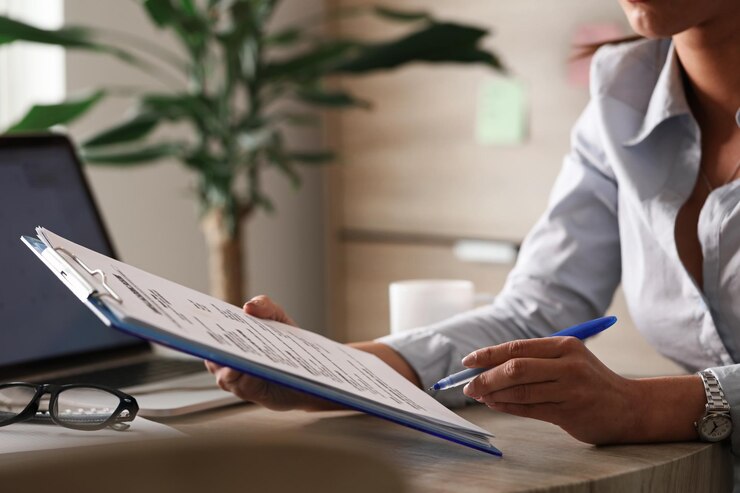 Kostenlose Foto nicht erkennbare unternehmerin, die geschäftsberichte analysiert, während sie im büro an papierkram arbeitet