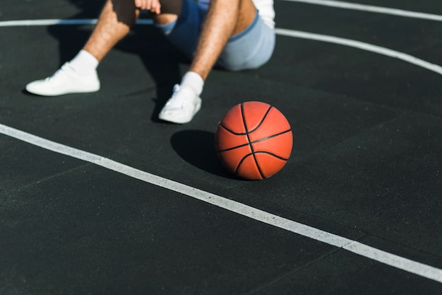 Nicht erkennbarer Athlet, der auf Basketballplatz sitzt