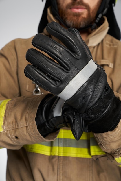 Kostenloses Foto nicht erkennbarer bärtiger feuerwehrmann mit lederschutzhandschuhen