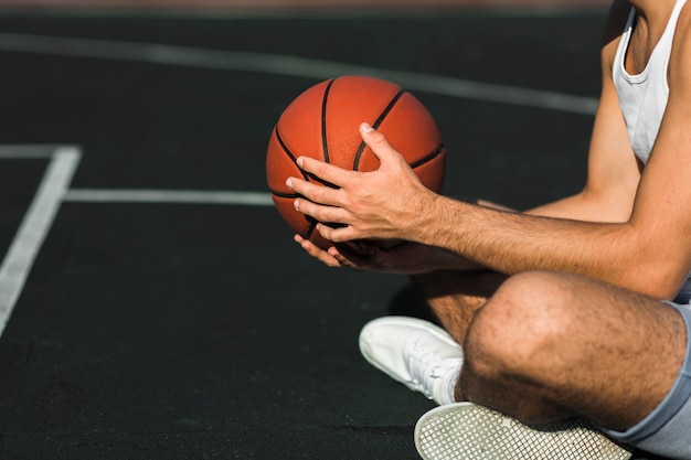 Nicht erkennbarer basketballspieler, der auf gericht sitzt