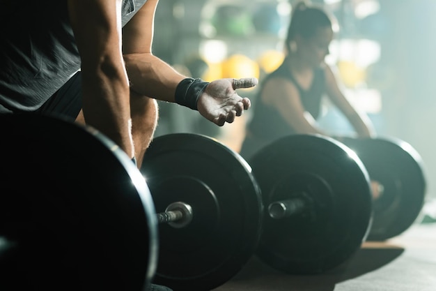 Nicht erkennbarer muskulöser Mann, der seine Hände mit Talkumpuder auf das Krafttraining im Fitnessclub vorbereitet. Fokus ist zur Hand